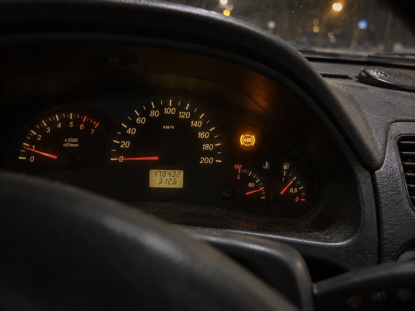 Приборная панель автомобиля ночью, на щитке горит жёлтая контрольная лампа ABS рядом со спидометром